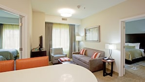 Une chambre d’hôtel comprenant un lit, un canapé, une chaise, une petite table et un bureau avec une lampe.