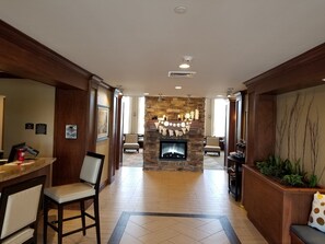 A hotel lobby with a stone fireplace, a reception desk, and a seating area. - Staybridge Suites Toledo - Rossford - Perrysburg by IHG (Perrysburg)