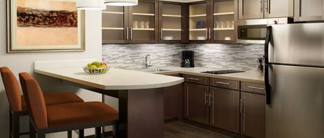 A modern kitchen with a central island, stainless steel appliances, and a tiled backsplash.