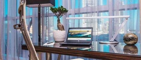 A modern office desk with a laptop, a potted plant, and a decorative sphere.