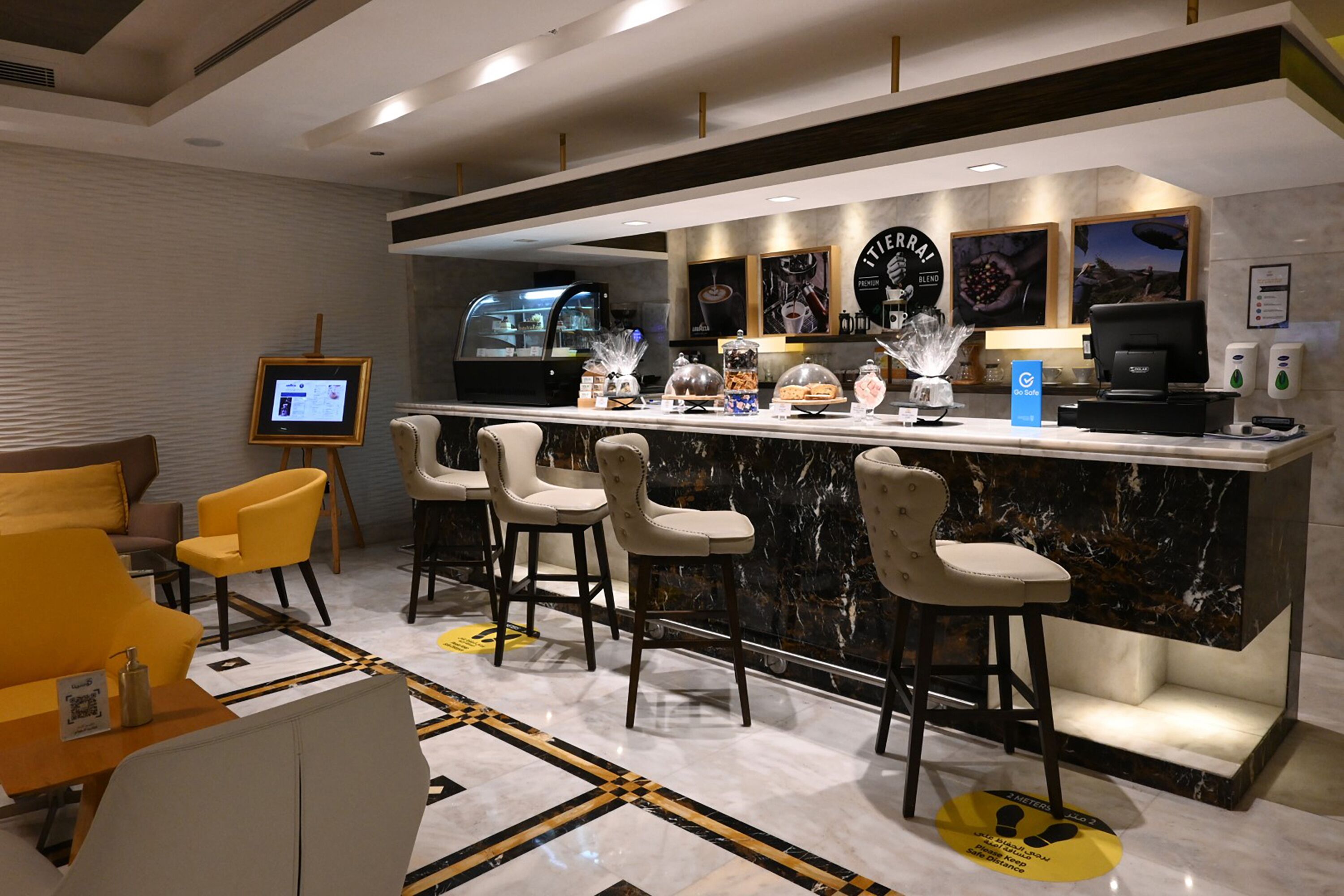 Un área de bar moderna con una encimera de mármol, taburetes y una pantalla digital.