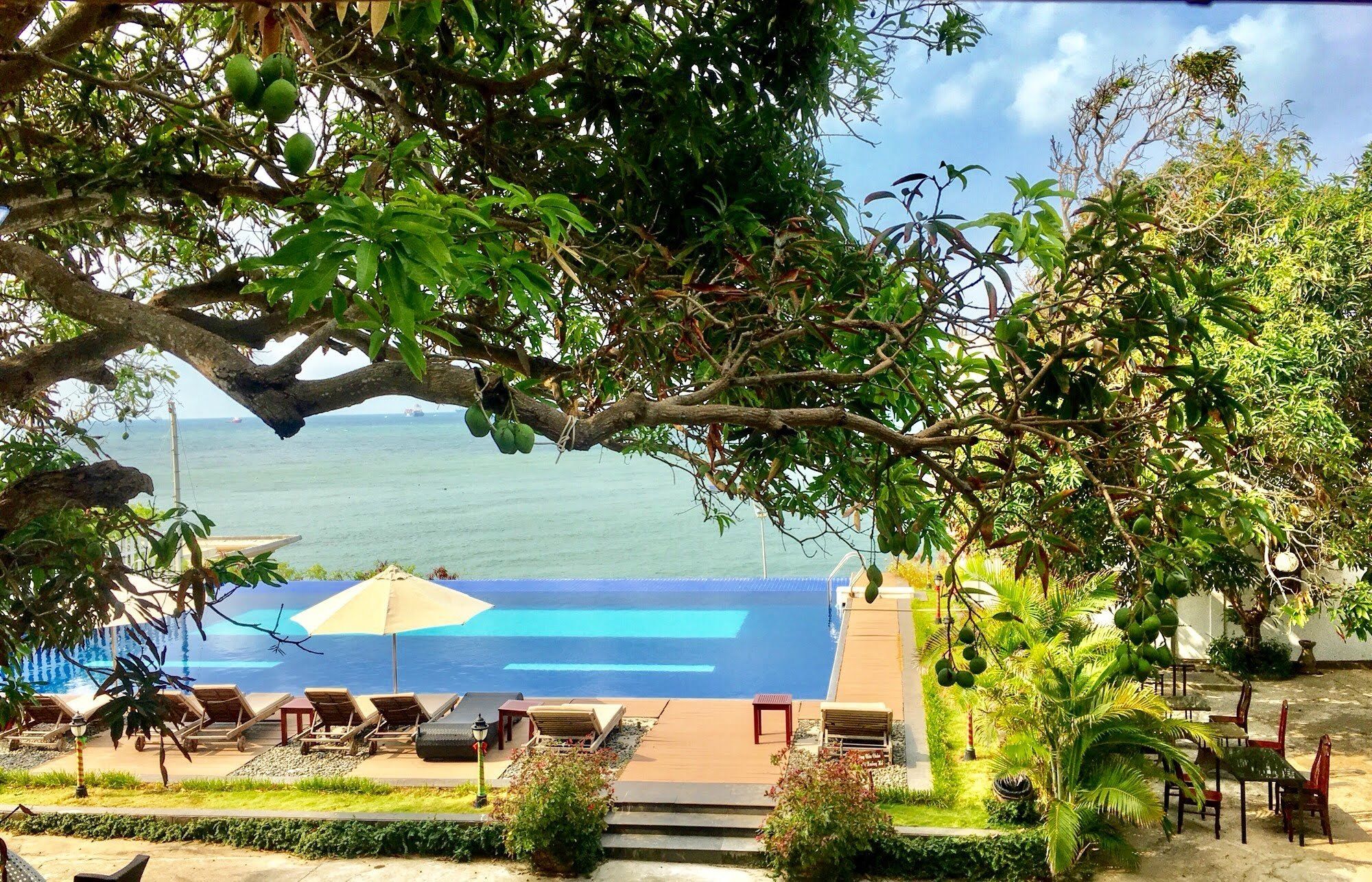 A poolside area with lounge chairs and a view of the sea.