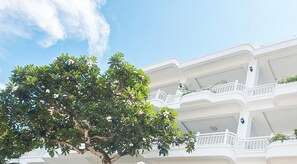 A multi-story building with white balconies and a large tree in the foreground. - SV Boutique Resort (Ho Chi Minh City)