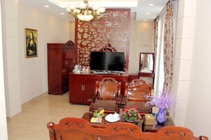 A living room with a TV, wooden furniture, and a decorative partition.
