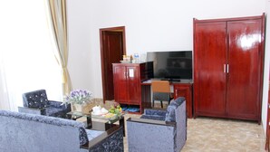 A living room with a sofa set, a glass coffee table, a TV, and a wardrobe. - Tran Vinh Hotel (Bac Lieu)