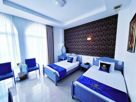 A hotel room with two beds, a sitting area, and a large window.