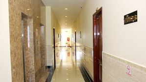 A hotel corridor with marble walls, a wooden door, and a 'No Smoking' sign. - Tran Vinh Hotel (Bac Lieu)