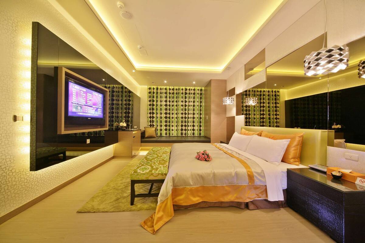 A modern hotel room with a large bed, a TV, a seating area, and a bathroom.