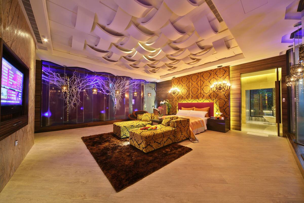 A modern hotel room with a large bed, a sofa, and a TV.