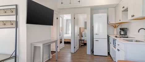 A modern kitchen with white cabinets, a built-in oven, and a coffee machine.