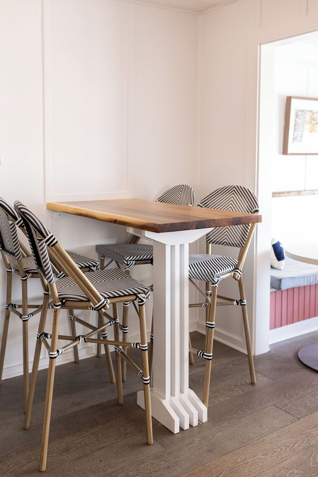 Habitación de esquina con una mesa de madera y cuatro sillas con cojines a rayas.