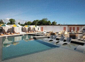 Una piscina al aire libre, sombrillas, tumbonas