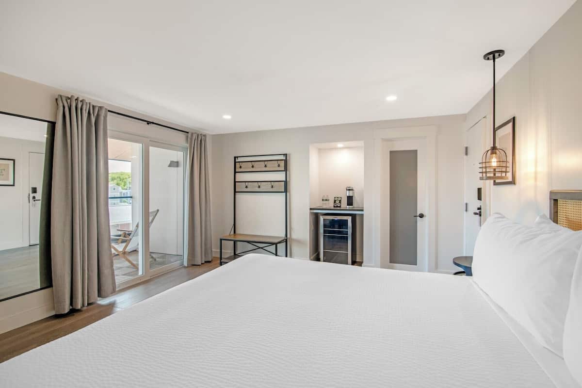 A bedroom with a large bed, a small table, a wardrobe, and a kitchenette.