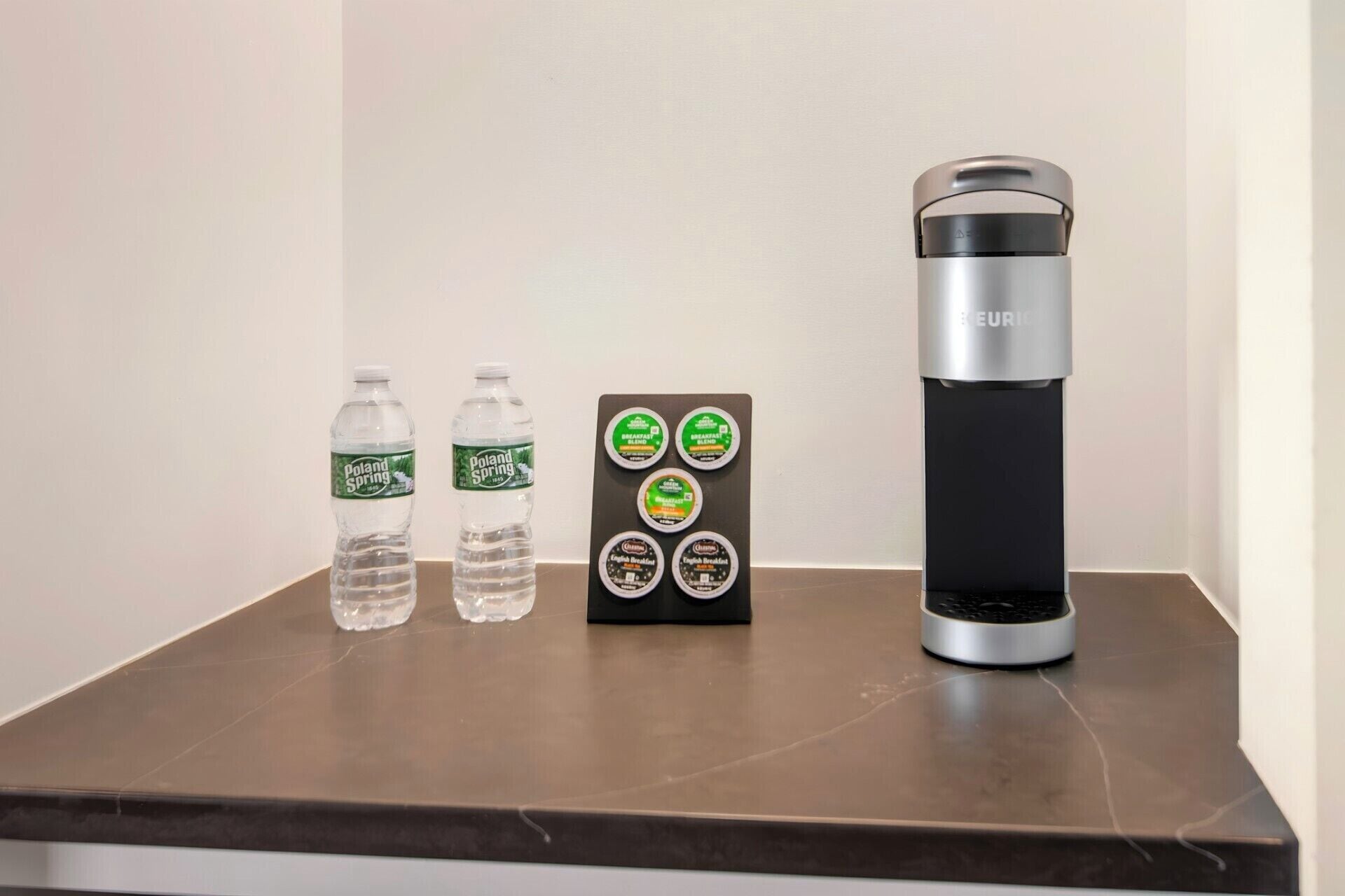 Une table avec deux bouteilles d’eau, un thermos et un plateau contenant divers aliments pour le petit-déjeuner.