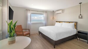 A hotel room with a bed, a chair, a table, and a view of the ocean. - Ocean Surf at York Beach (York Beach)