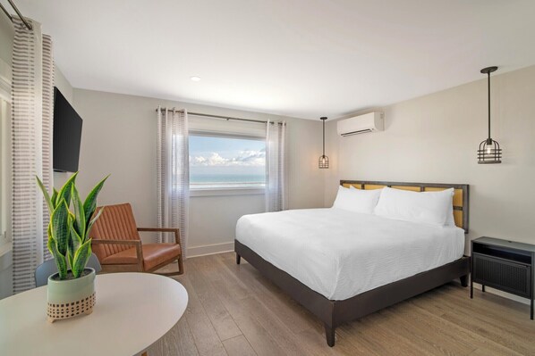 A hotel room with a bed, a chair, a table, and a view of the ocean. - Ocean Surf at York Beach (York Beach)
