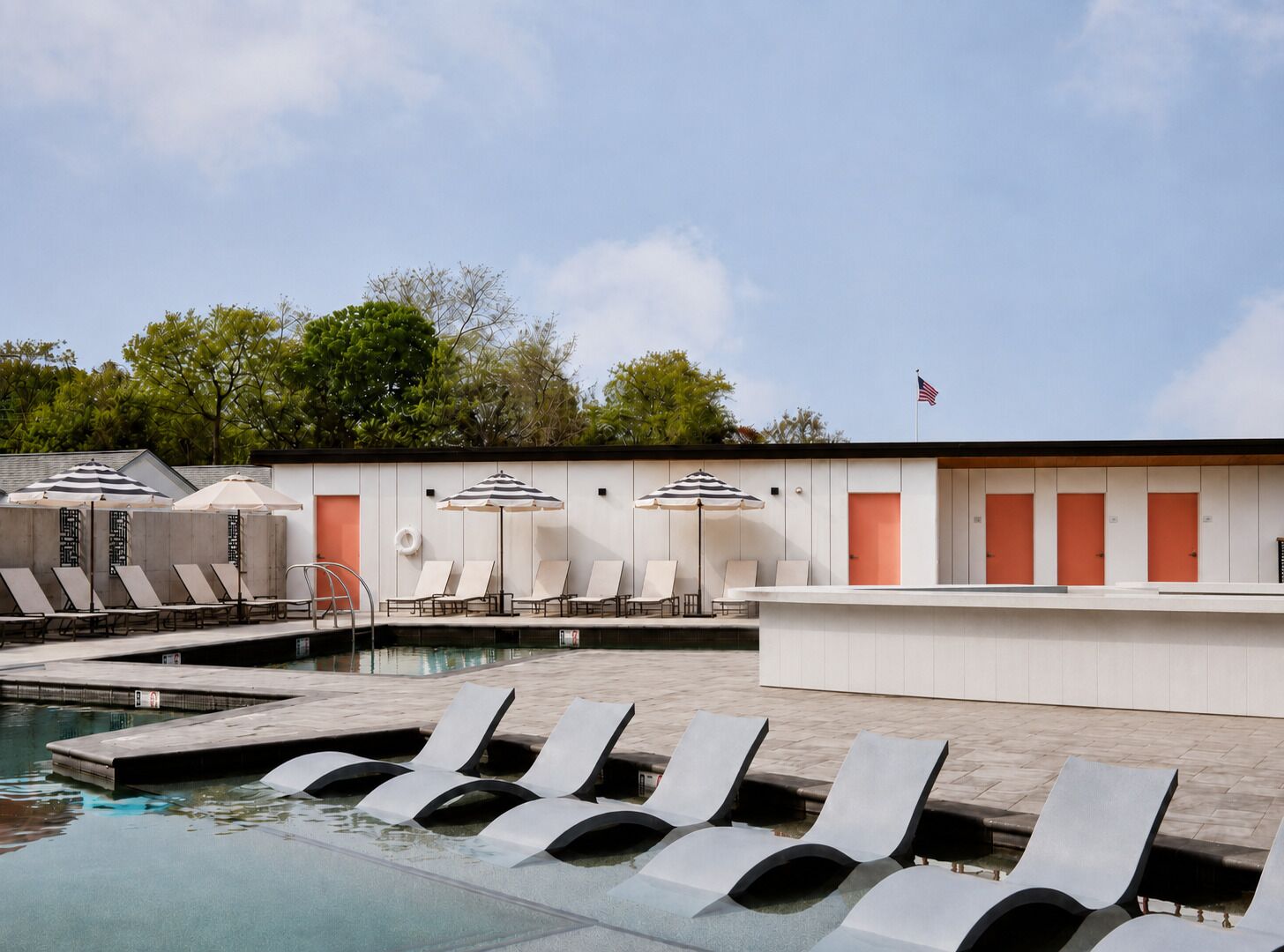 Una piscina al aire libre, sombrillas, sillones reclinables de piscina