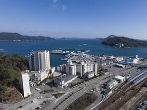 An aerial view of a coastal city with modern buildings, a marina, and a railway line.