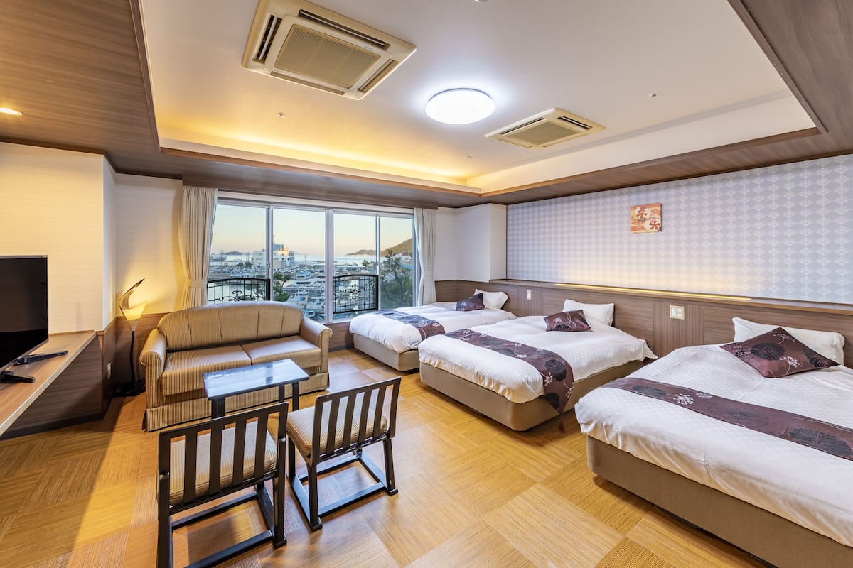 A hotel room with two beds, a sofa, a small table, and a TV.
