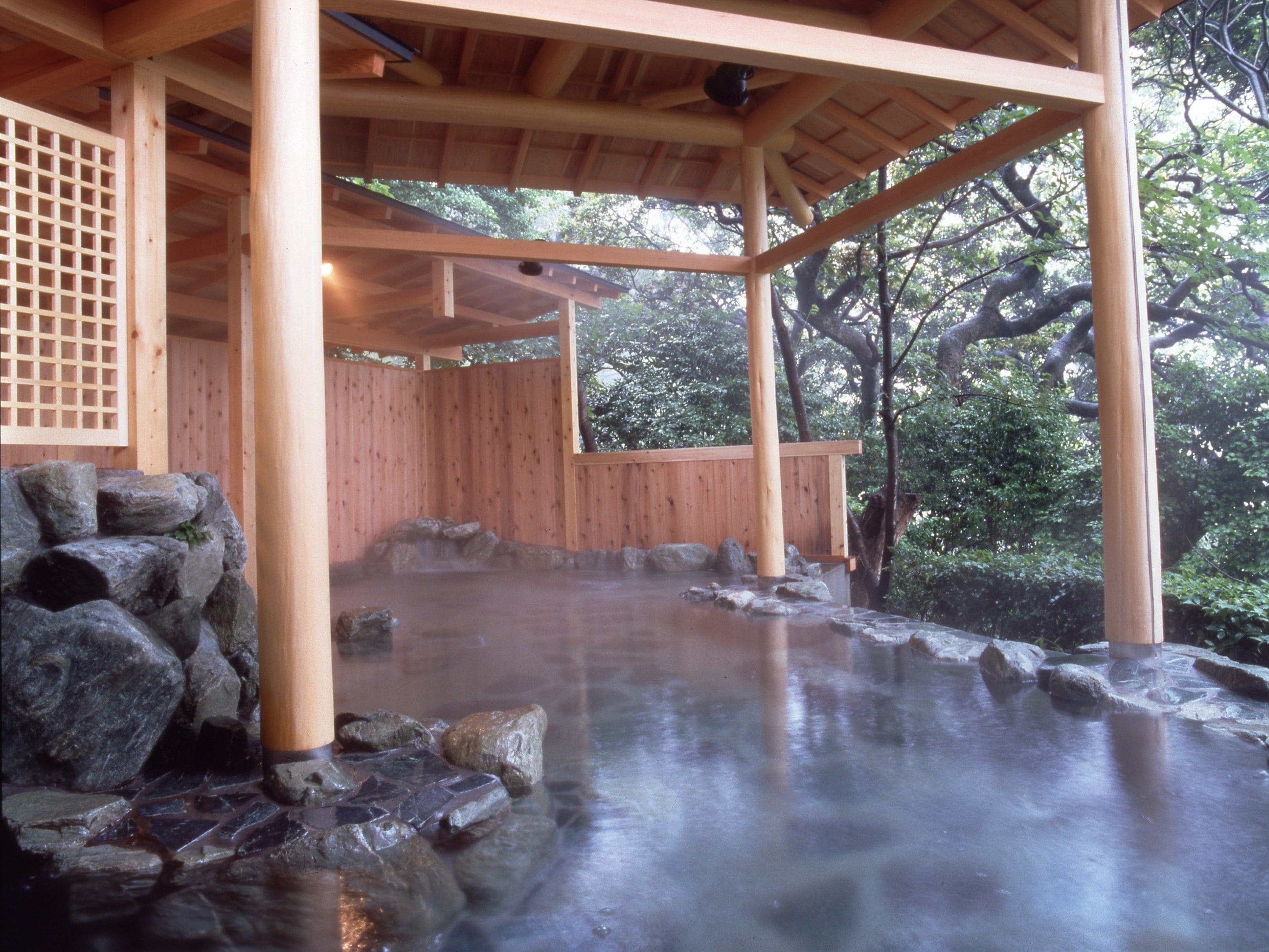 A traditional wooden structure with a stone-lined hot spring area.