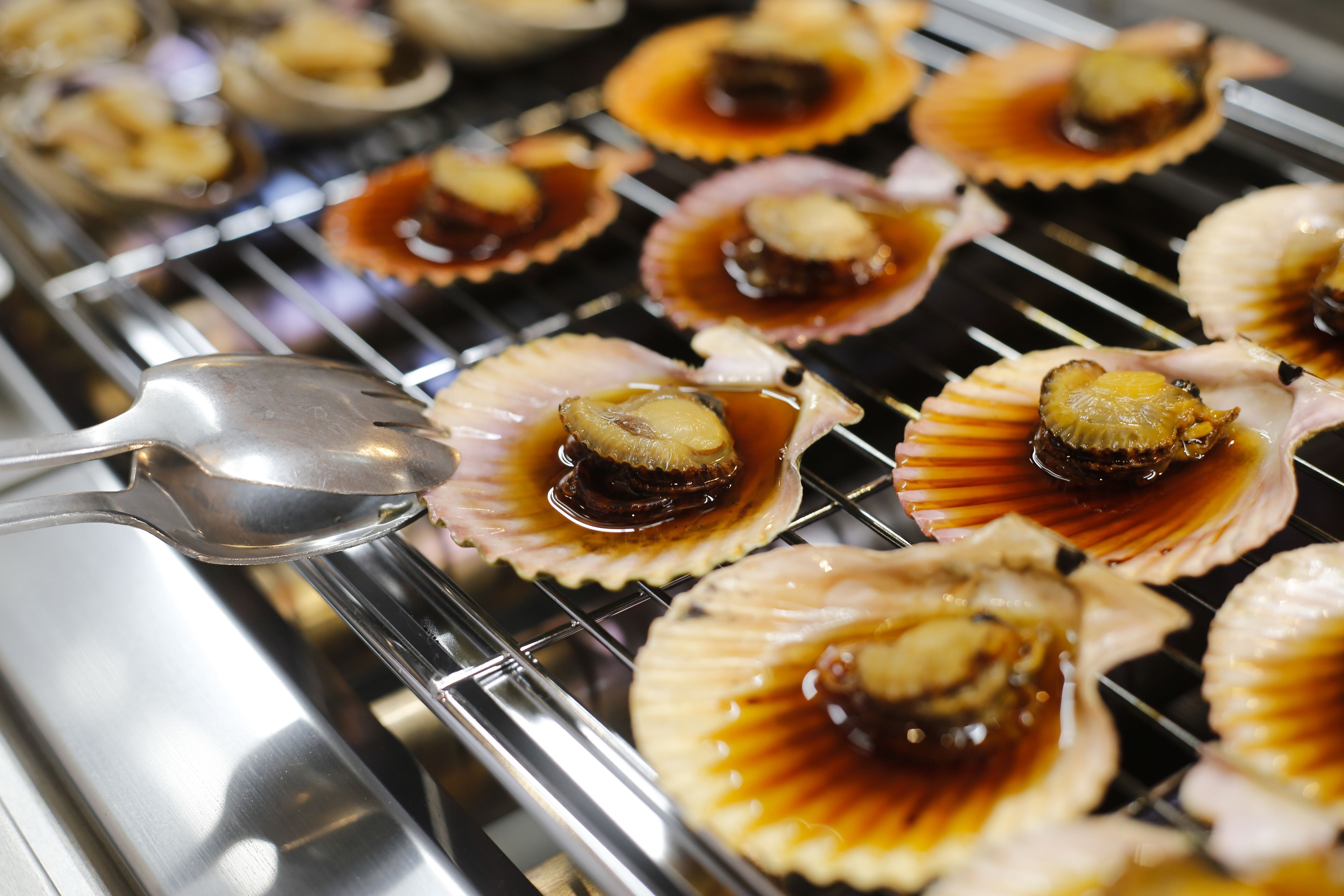 A tray of cooked scallops on a grill.