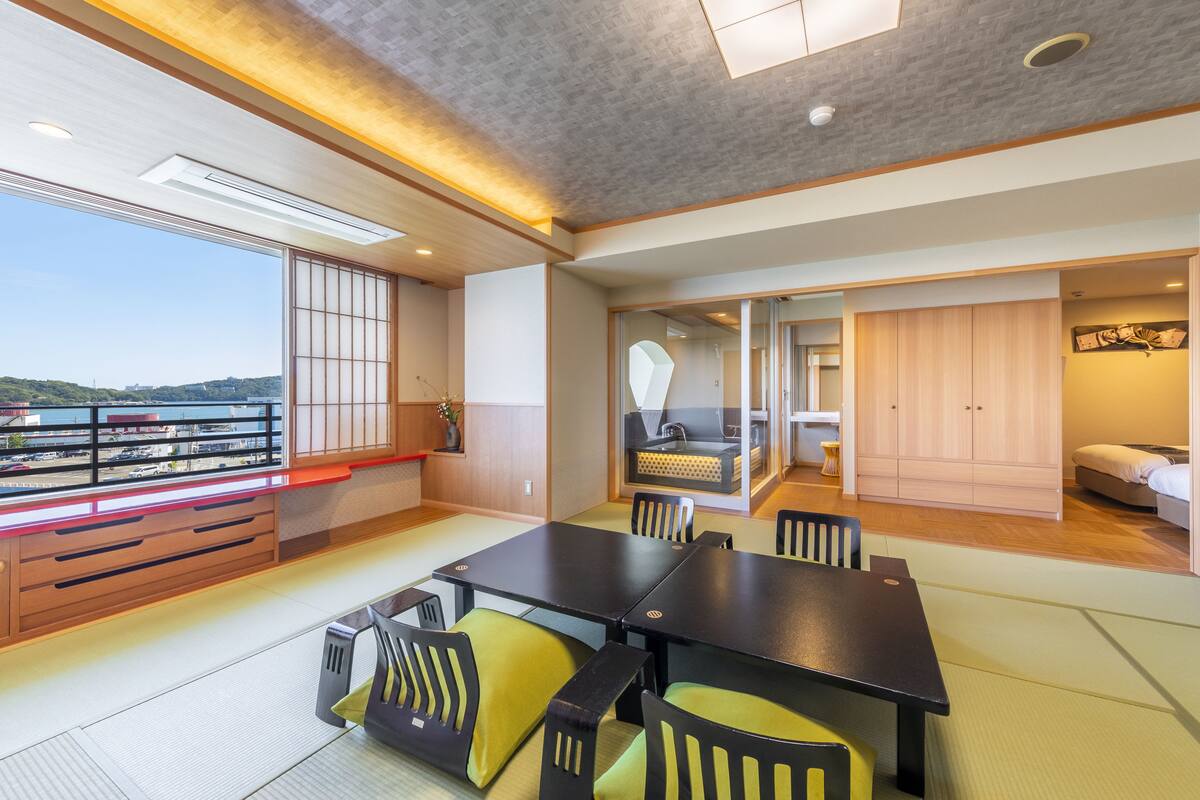 A modern interior with a dining area, a sofa, and a view of the city.