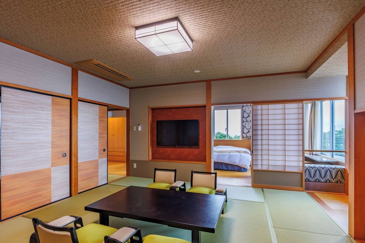 A traditional Japanese-style room with tatami flooring, a tatami mat table, and low wooden furniture.