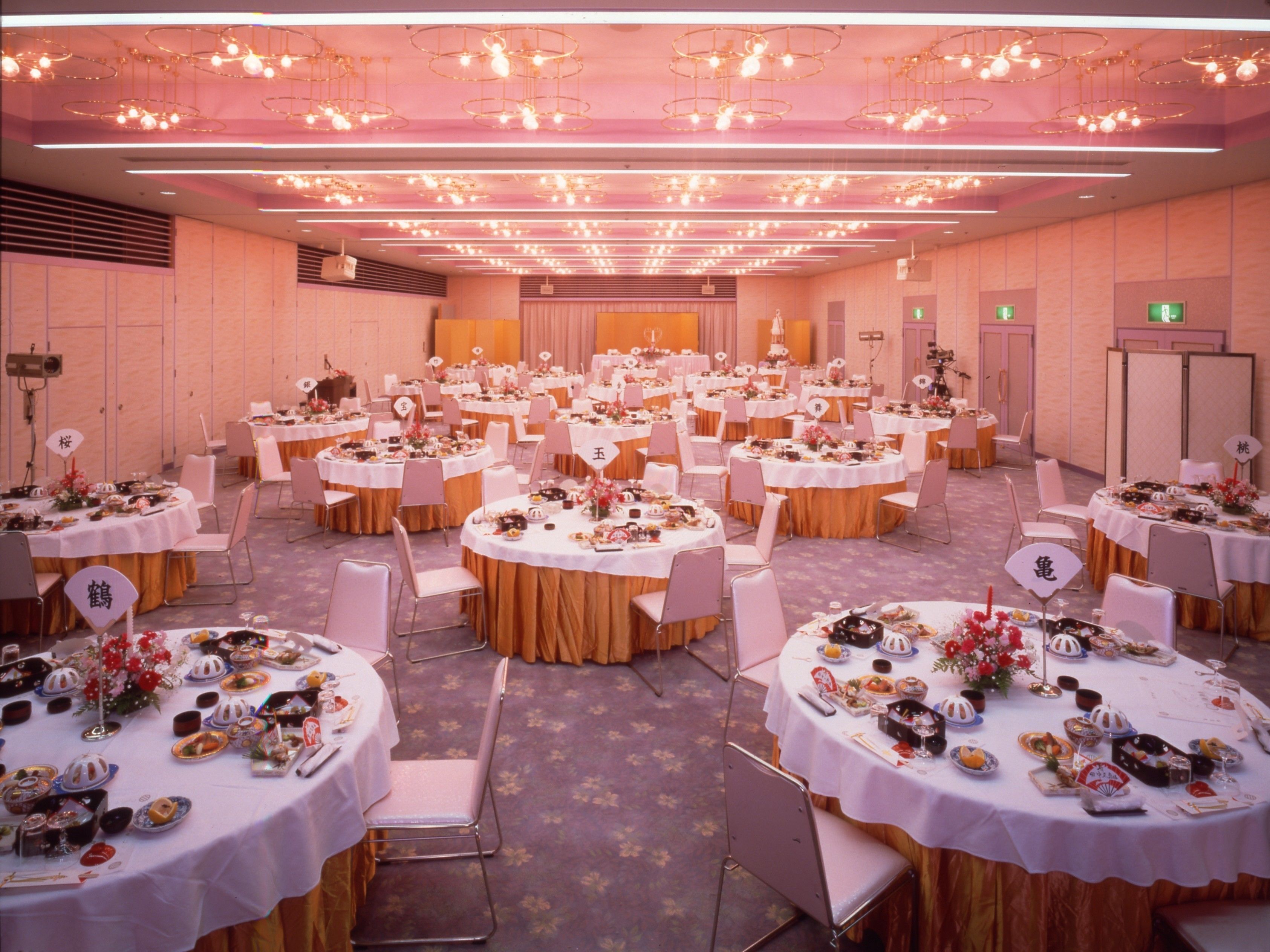 A banquet hall with round tables set for a formal event, featuring white tablecloths and floral centerpieces.