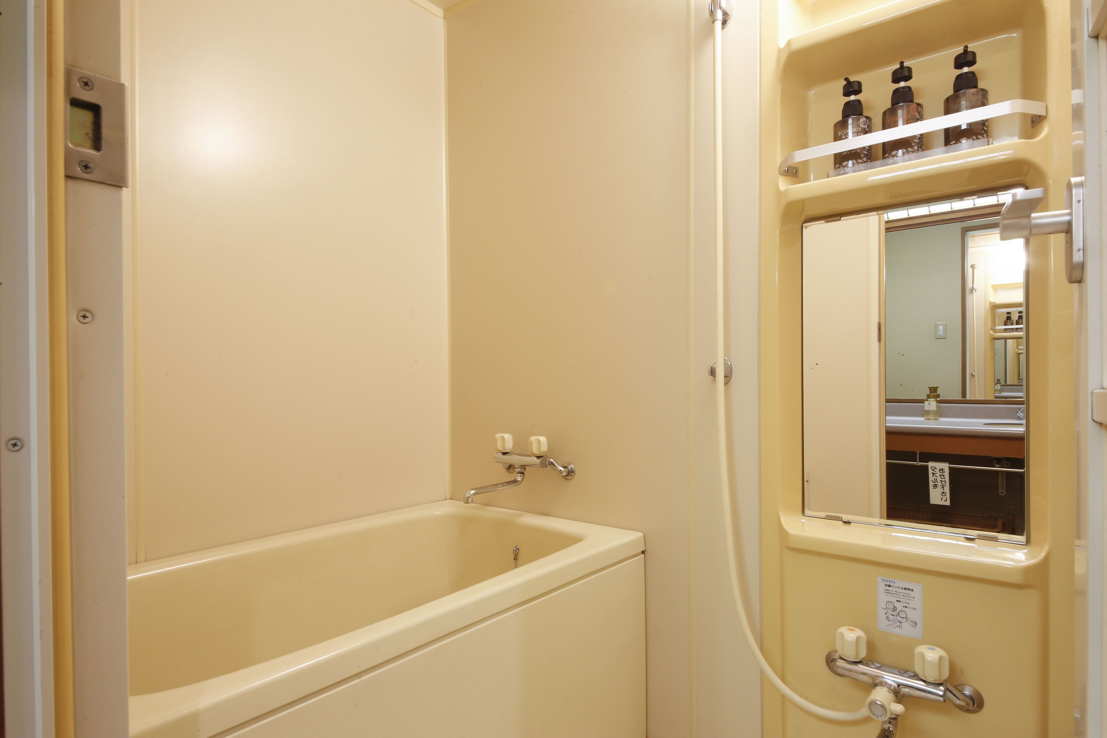 Un bagno con una vasca, uno specchio e uno scaffale con flaconi.
