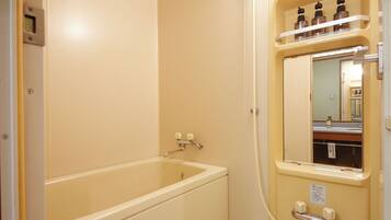 A bathroom with a bathtub, a mirror, and a shelf with bottles.