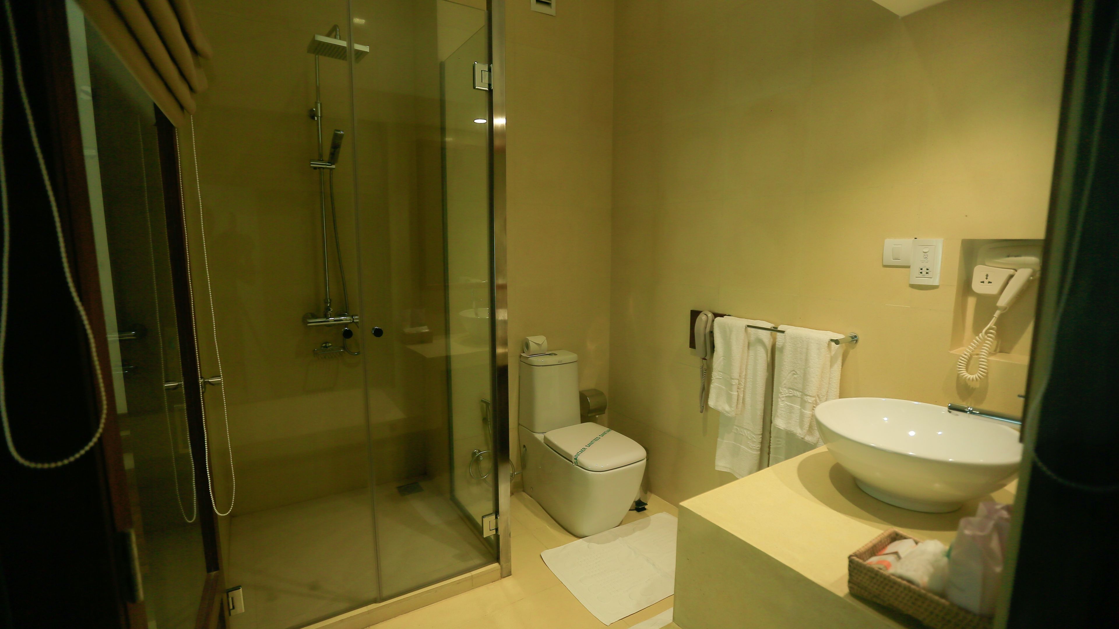 Un baño con ducha de vidrio, inodoro, lavabo y teléfono.