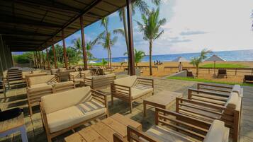 A beachside lounge with wooden furniture and a view of the ocean.