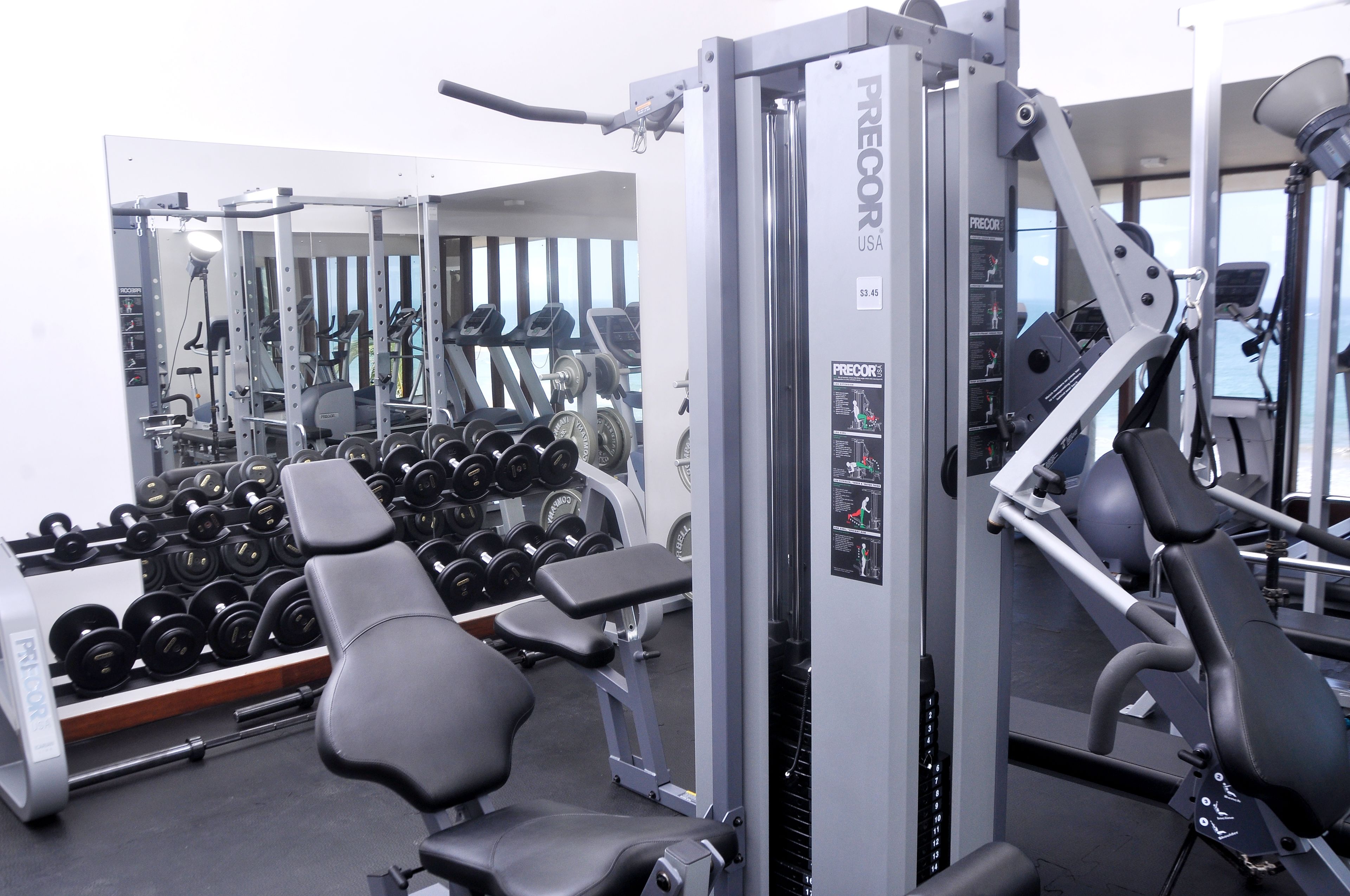 A gym with various exercise equipment, including dumbbells, benches, and weight machines.