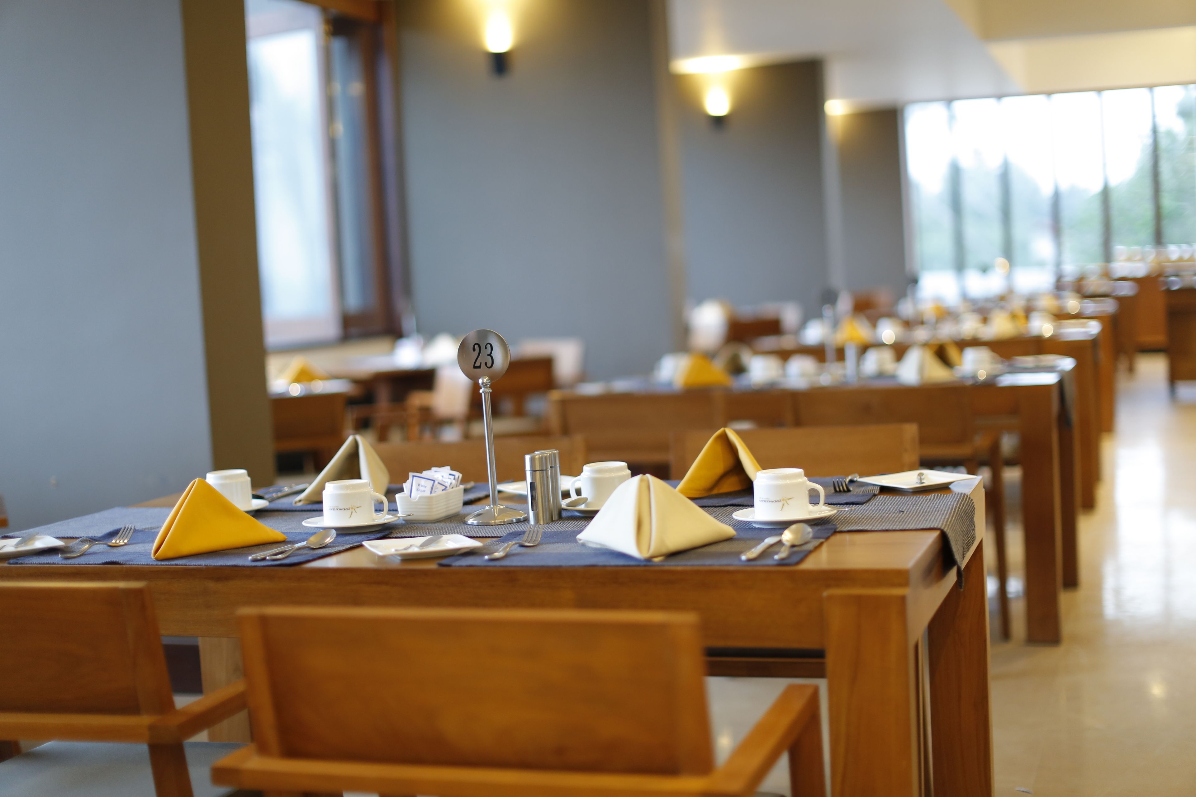 A dining area with tables set for service, numbered signs, and wooden chairs.