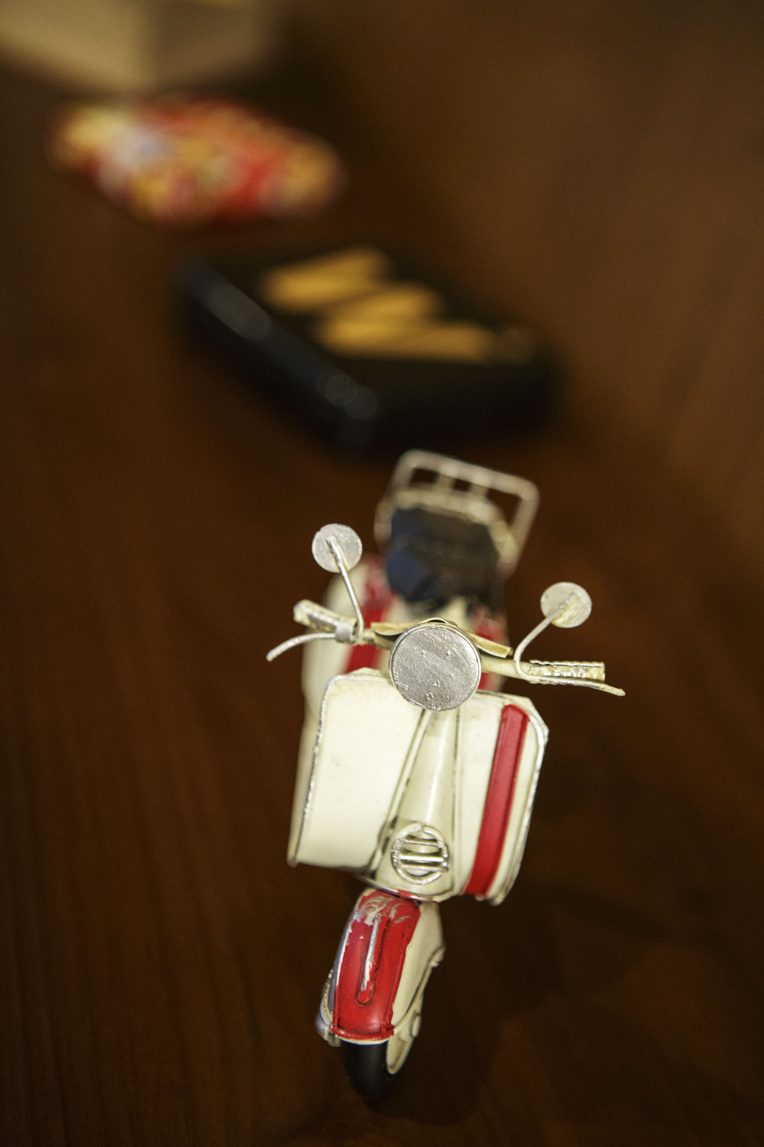Een close-up van een klassieke scooter met een rood-wit kleurenschema, met een ronde koplamp en een klein spiegeltje op het stuur.