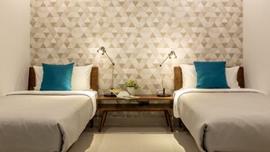 Une chambre d’hôtel avec deux lits, une table de chevet avec des lampes et un mur orné d’un motif géométrique.
