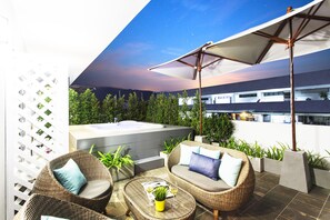 Eine Dachterrasse mit Korbmöbeln, einem Whirlpool und Topfpflanzen.
