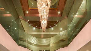 A modern lobby with a chandelier, a reception desk, and a staircase. - Akshaya Aura (Bengaluru)