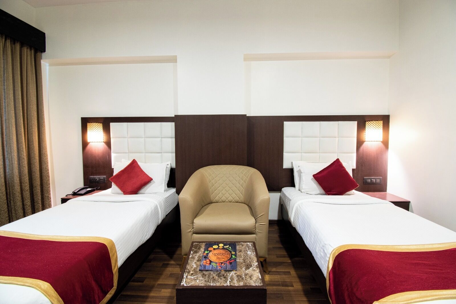 Ein Hotelzimmer mit zwei Betten, einem zentral platzierten Sessel und einem kleinen Tisch mit einem Gesellschaftsspiel.