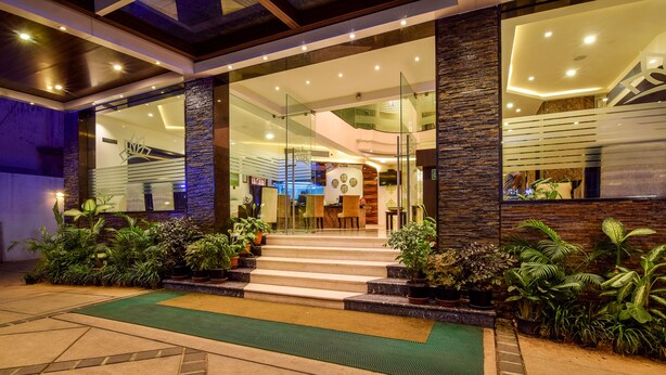 A modern hotel entrance with glass doors, a staircase, and a green mat. - Akshaya Aura (Bengaluru)