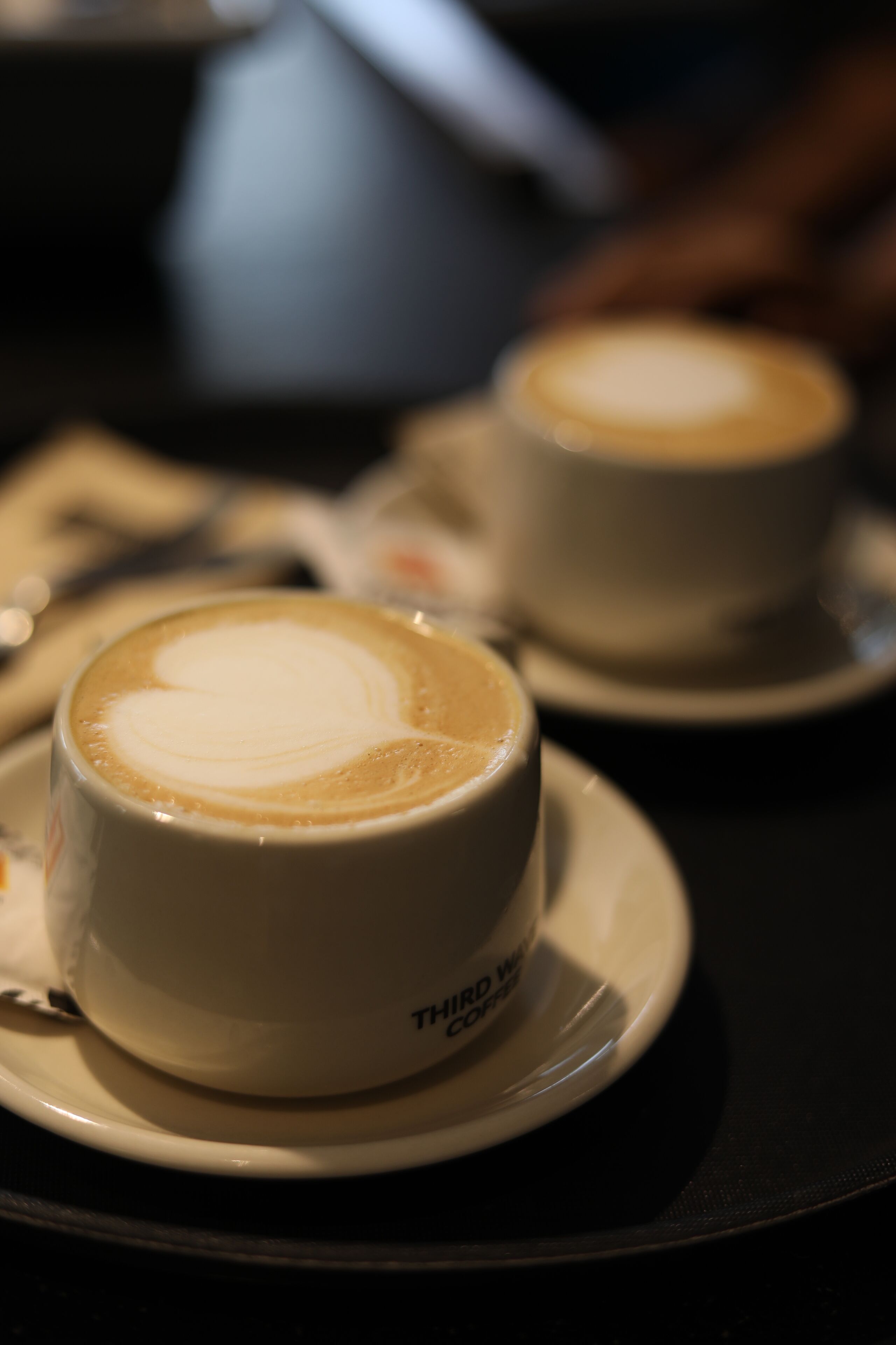 Two cups of coffee on saucers with a blurred background.