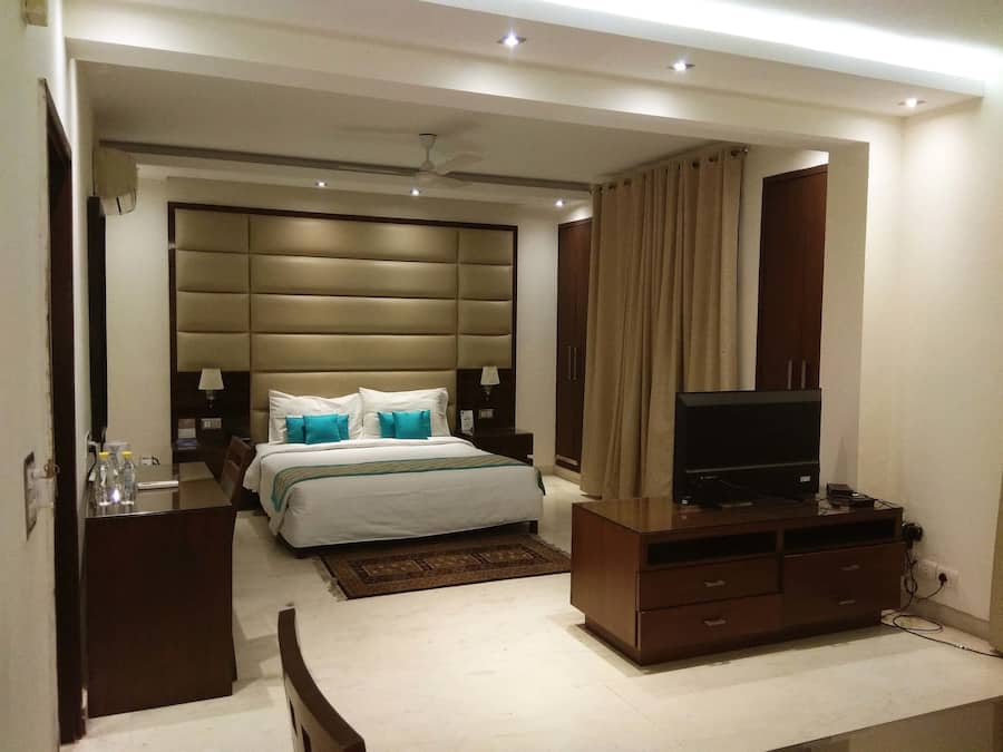Une chambre d’hôtel moderne équipée d’un grand lit, d’une télévision, d’une armoire et d’un bureau avec une lampe.