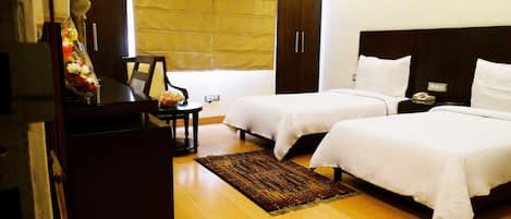 Habitación de hotel con dos camas, un escritorio, una silla y un armario.