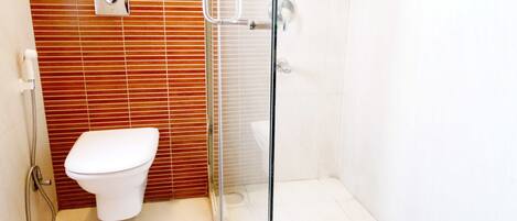 A modern bathroom with a glass-enclosed shower, a white toilet, and a wooden panel wall.