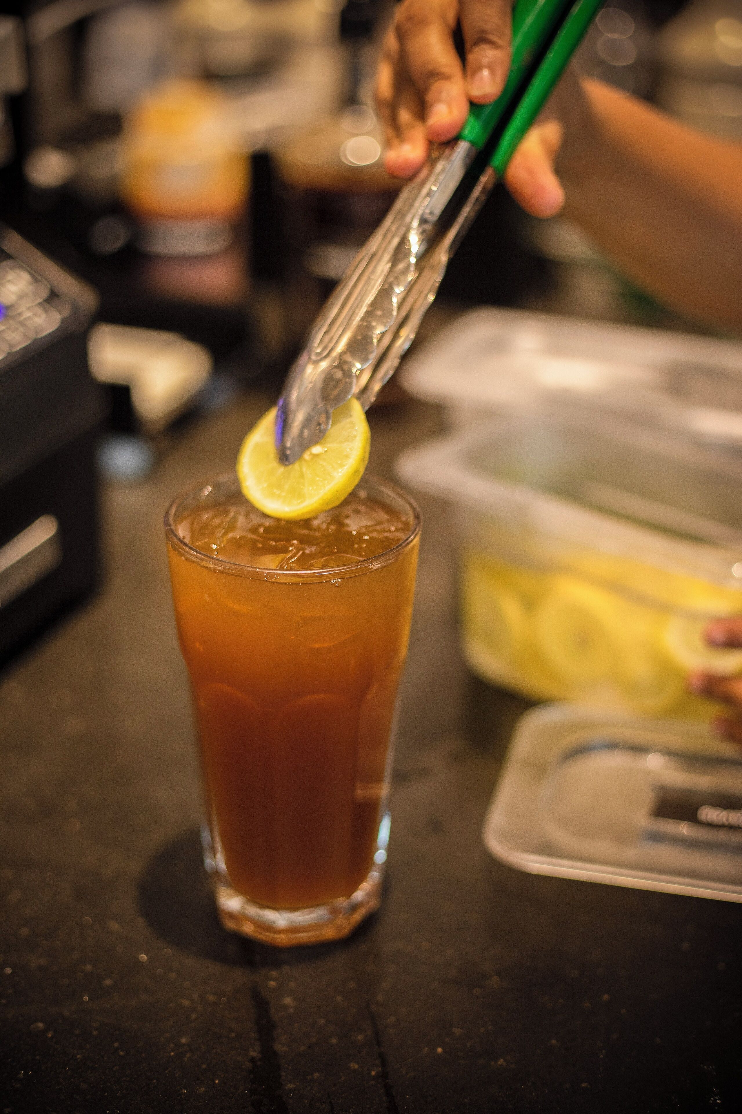 A glass of iced tea with a lemon slice on a bar counter.