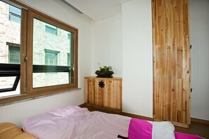 Une chambre à coucher avec un lit, une fenêtre, une armoire en bois et une garde-robe.