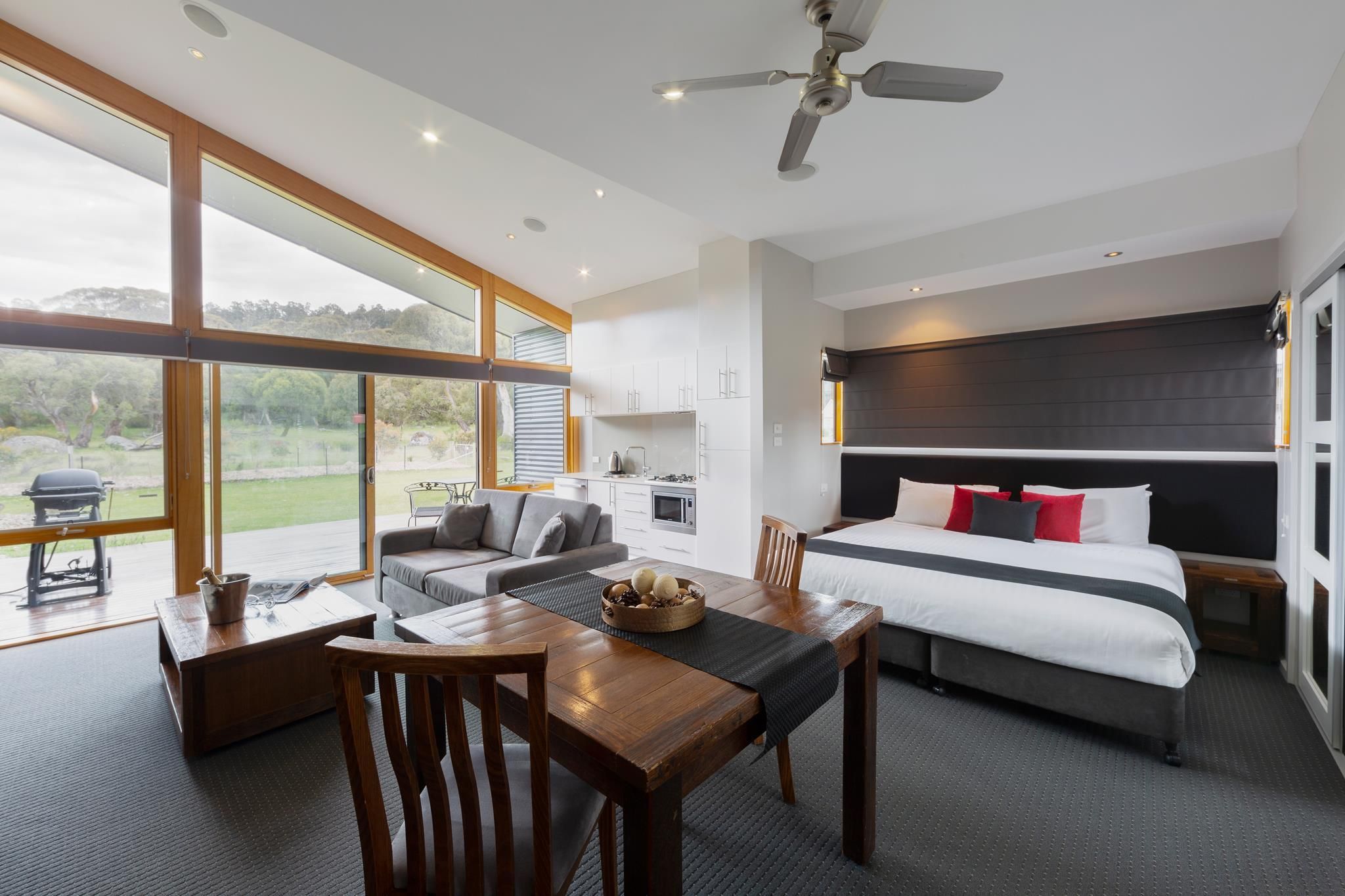 A modern hotel room with a large bed, a dining area, and a kitchenette.