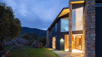 A modern house with a stone facade, large windows, and a well-lit entrance.