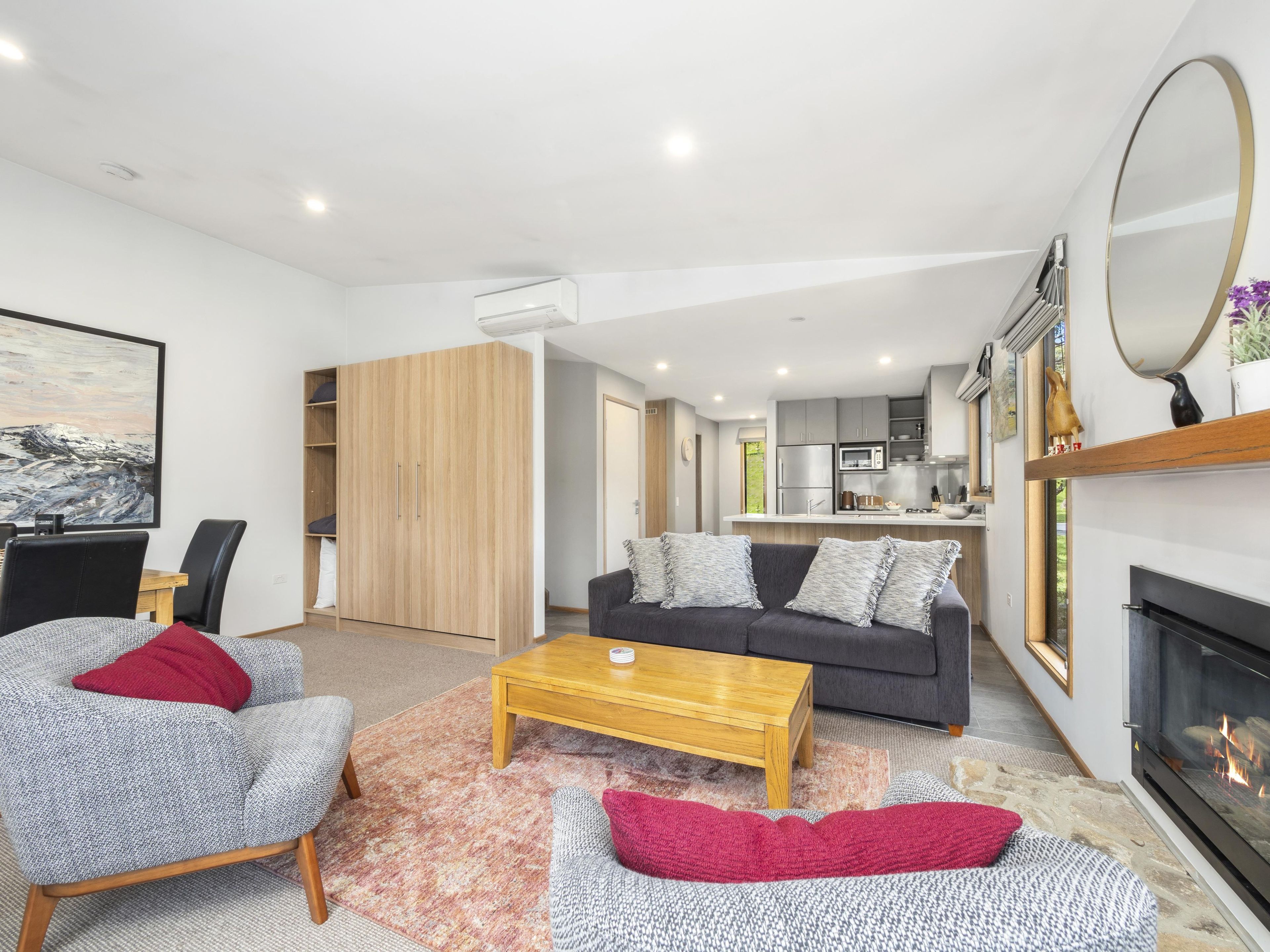 Una sala moderna con sofá, sillones, una mesa de centro y chimenea.