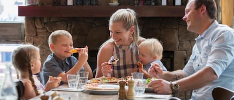 A family dining at a restaurant with a stone wall and shelves of bottles in the background.